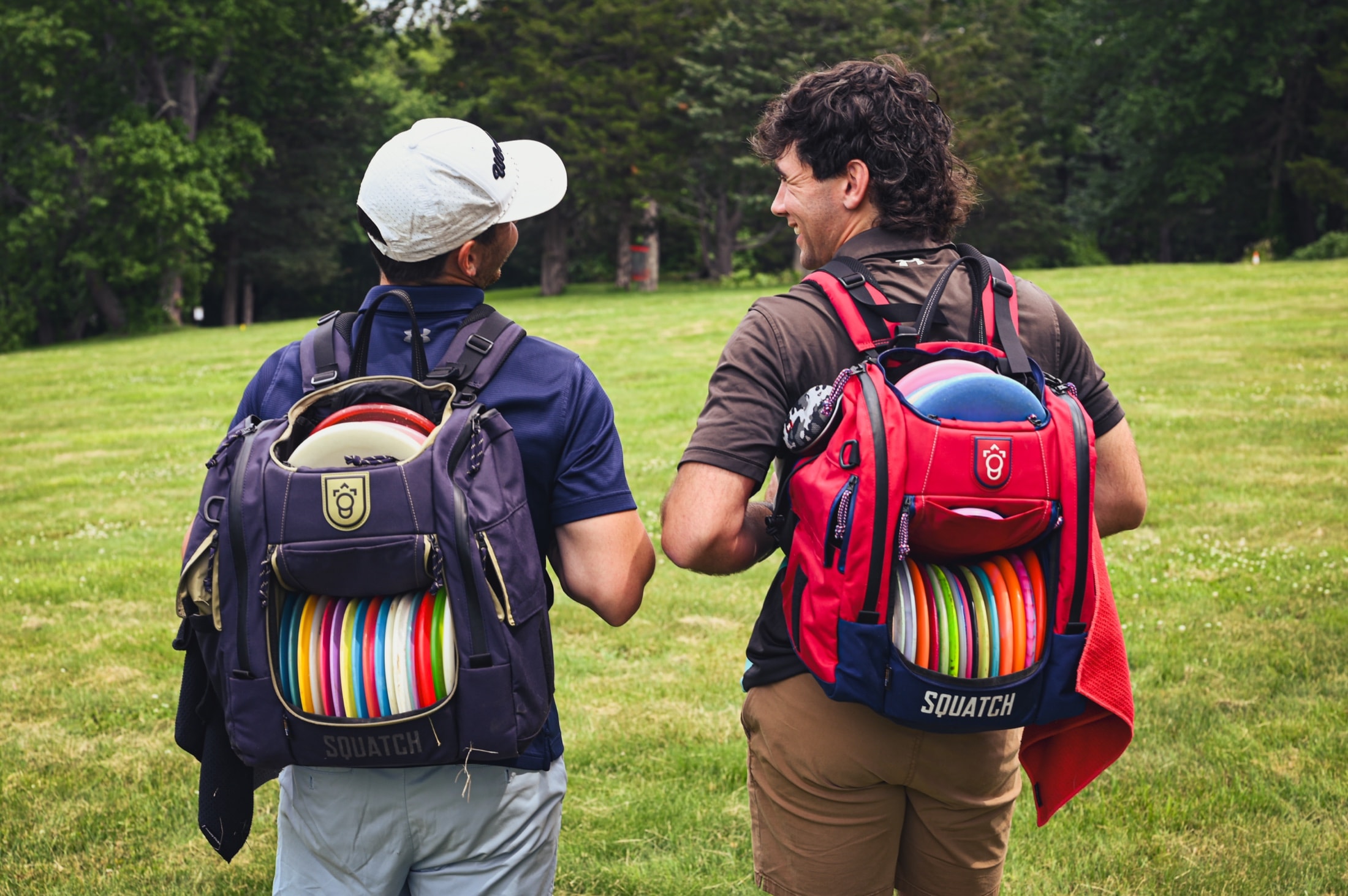 Two disc golfers walking the course with bags full of discs
