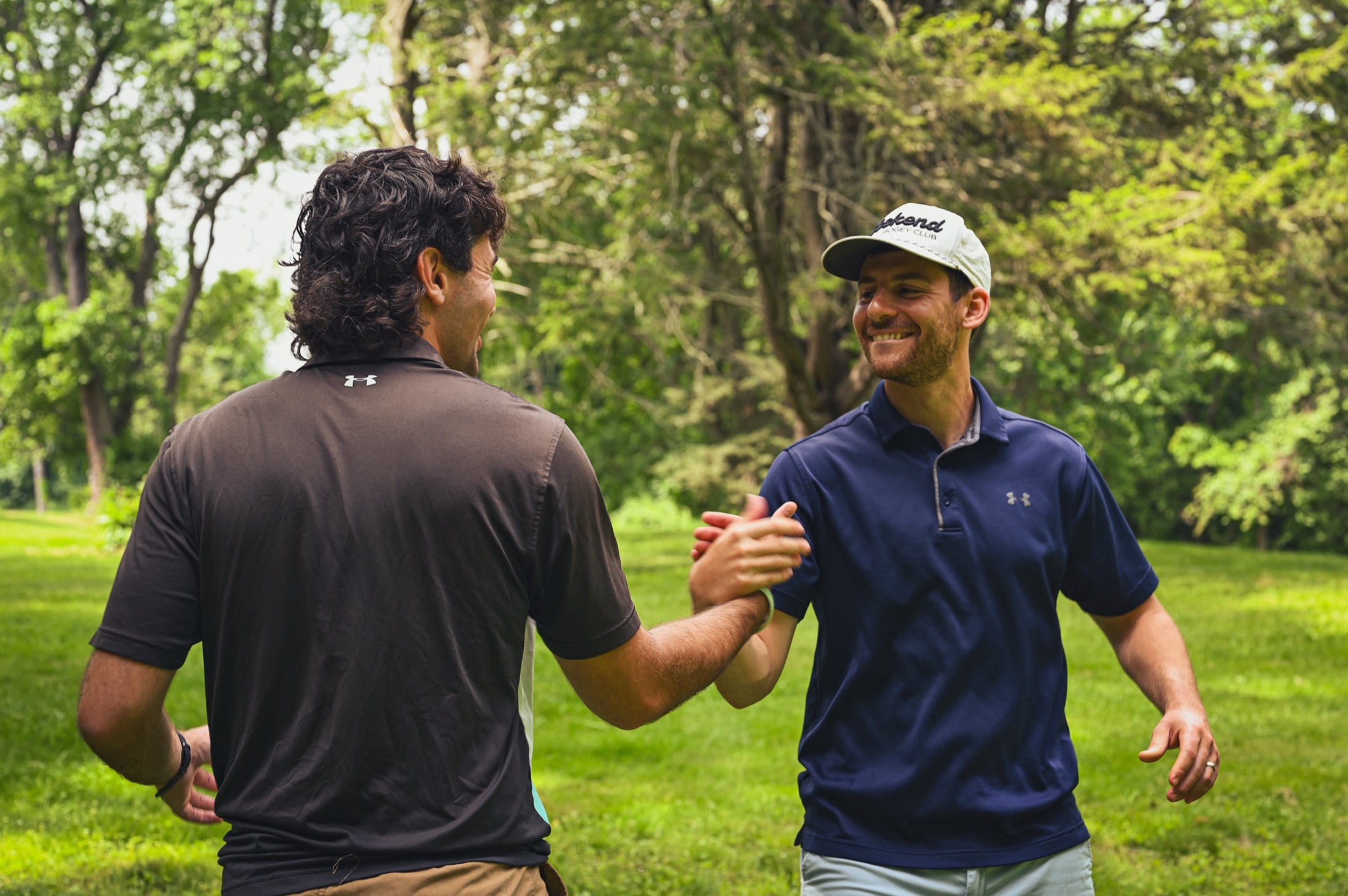 Two players greeting each other with a handshake on the course