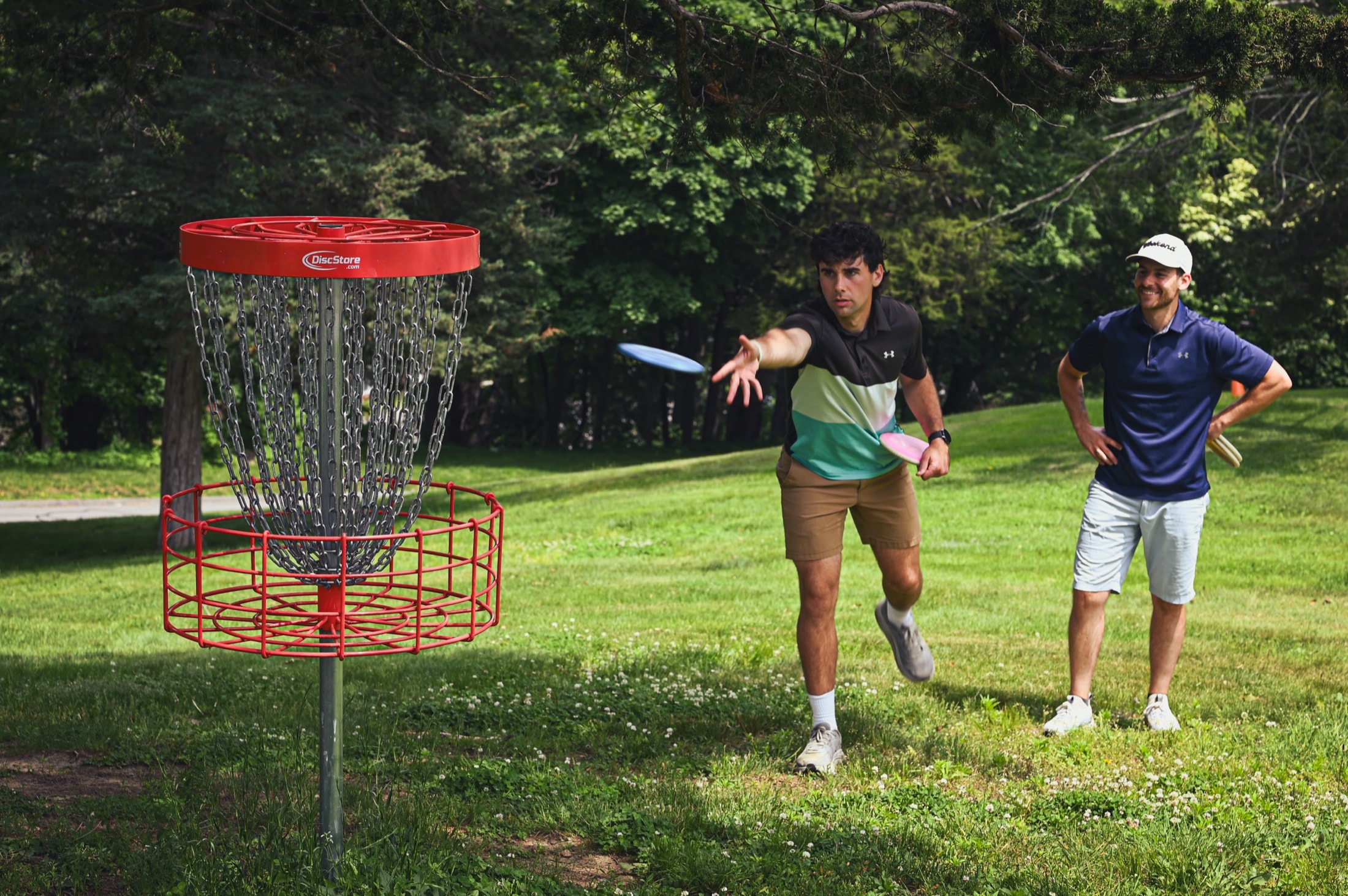 A player putting at the basket while a friend watches